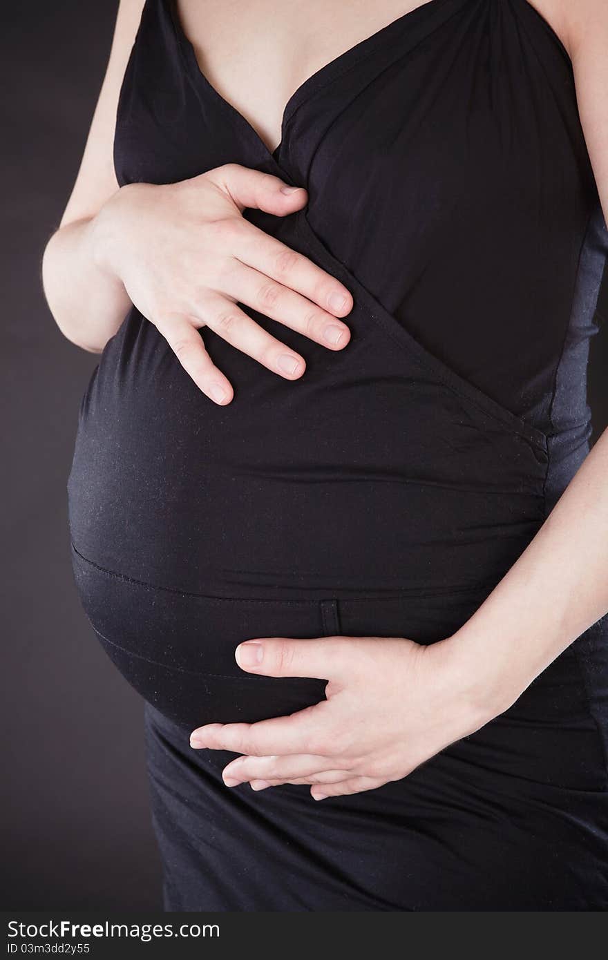 Young fresh pregnant woman with blow bubbles sitting on a couch over black background.