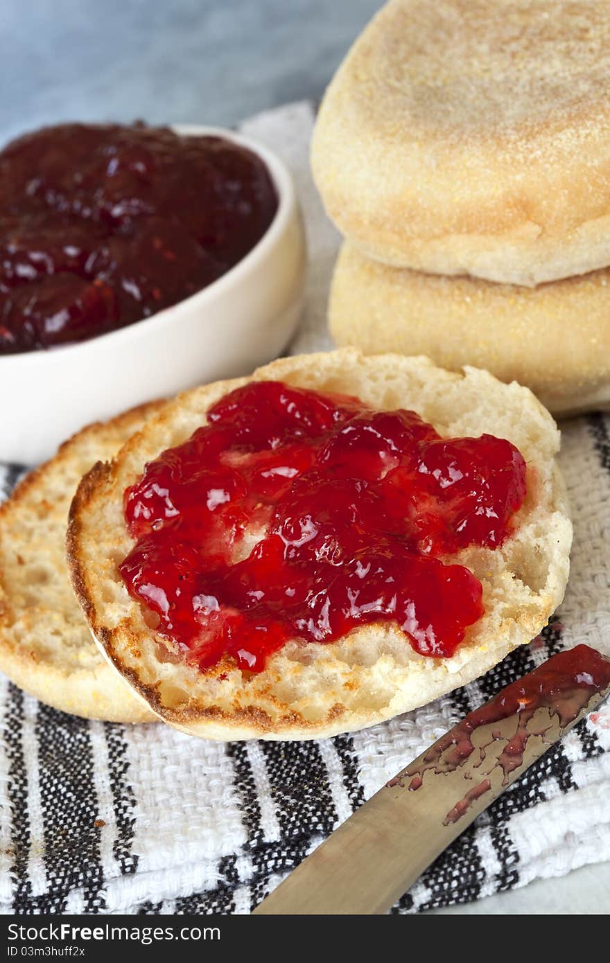 English muffins, one cut and spread with strawberry jam.