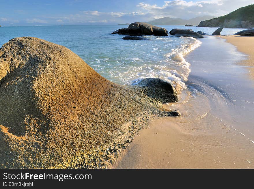 Rocky sea coast under sunset warm lighting