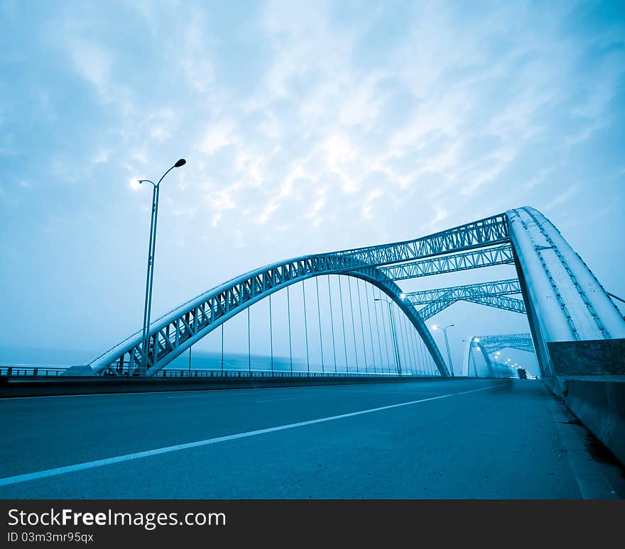 Road through the bridge with blue sky background of a city.