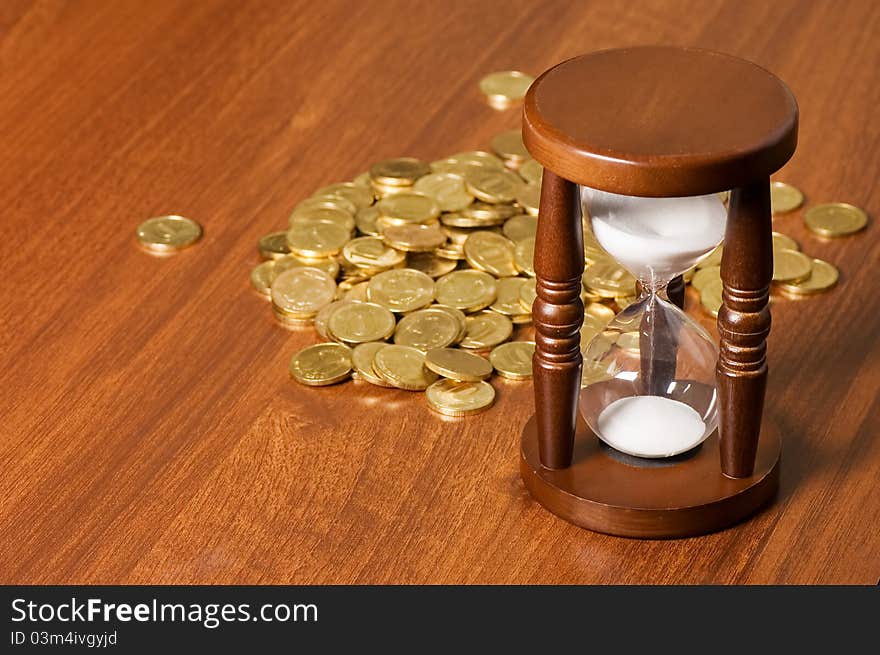 Hourglasses and coin On a wooden table still life. Hourglasses and coin On a wooden table still life