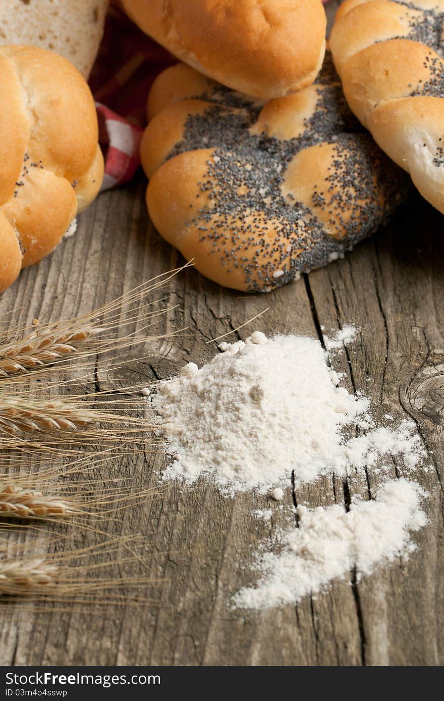 Lot of bread with spikes of rye and flour on old wooden table