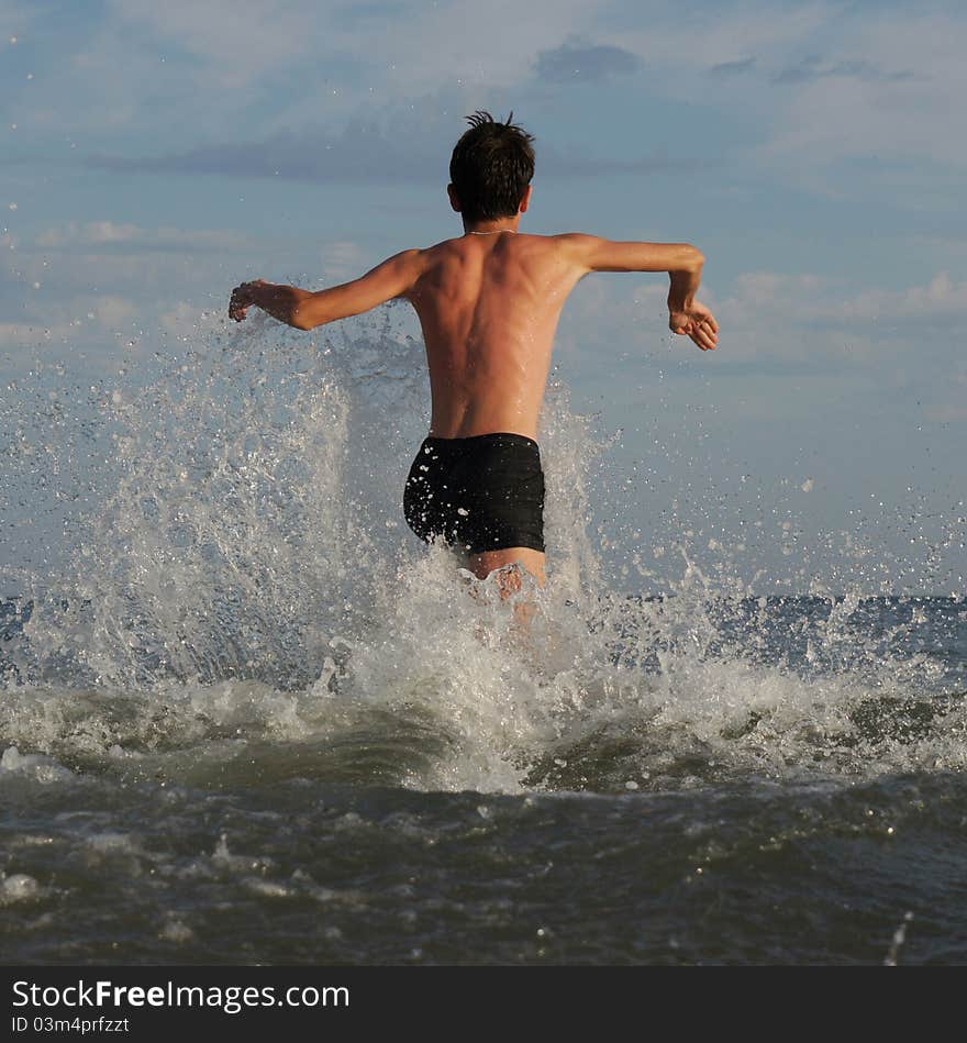 Boy running along the beach before swimming