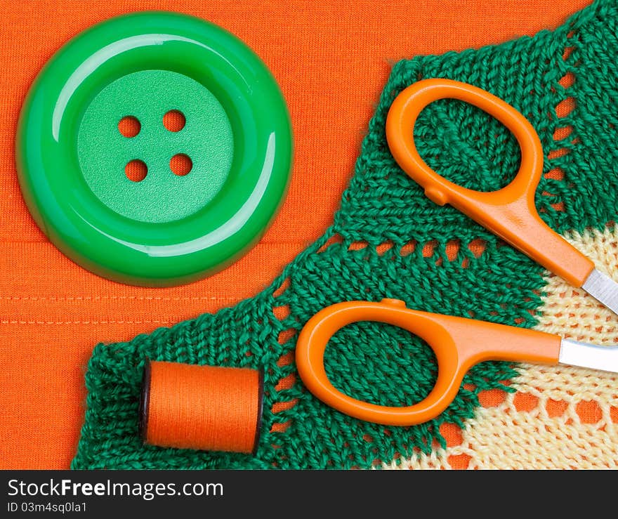 Scissors, button, threads on fabric background