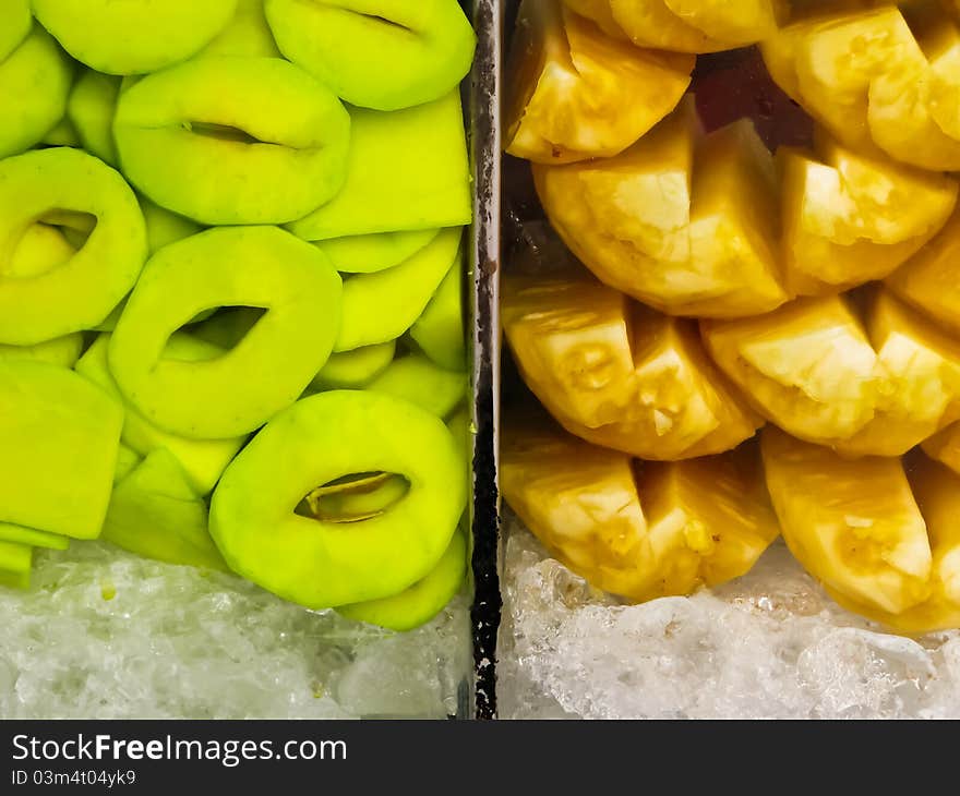 Fresh green mango and pineapple in glass case with ice. Fresh green mango and pineapple in glass case with ice