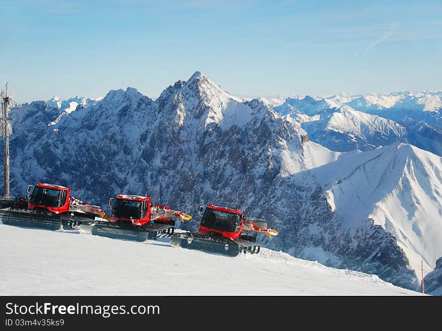 Piste preperation vehicles with view over the alps. Piste preperation vehicles with view over the alps