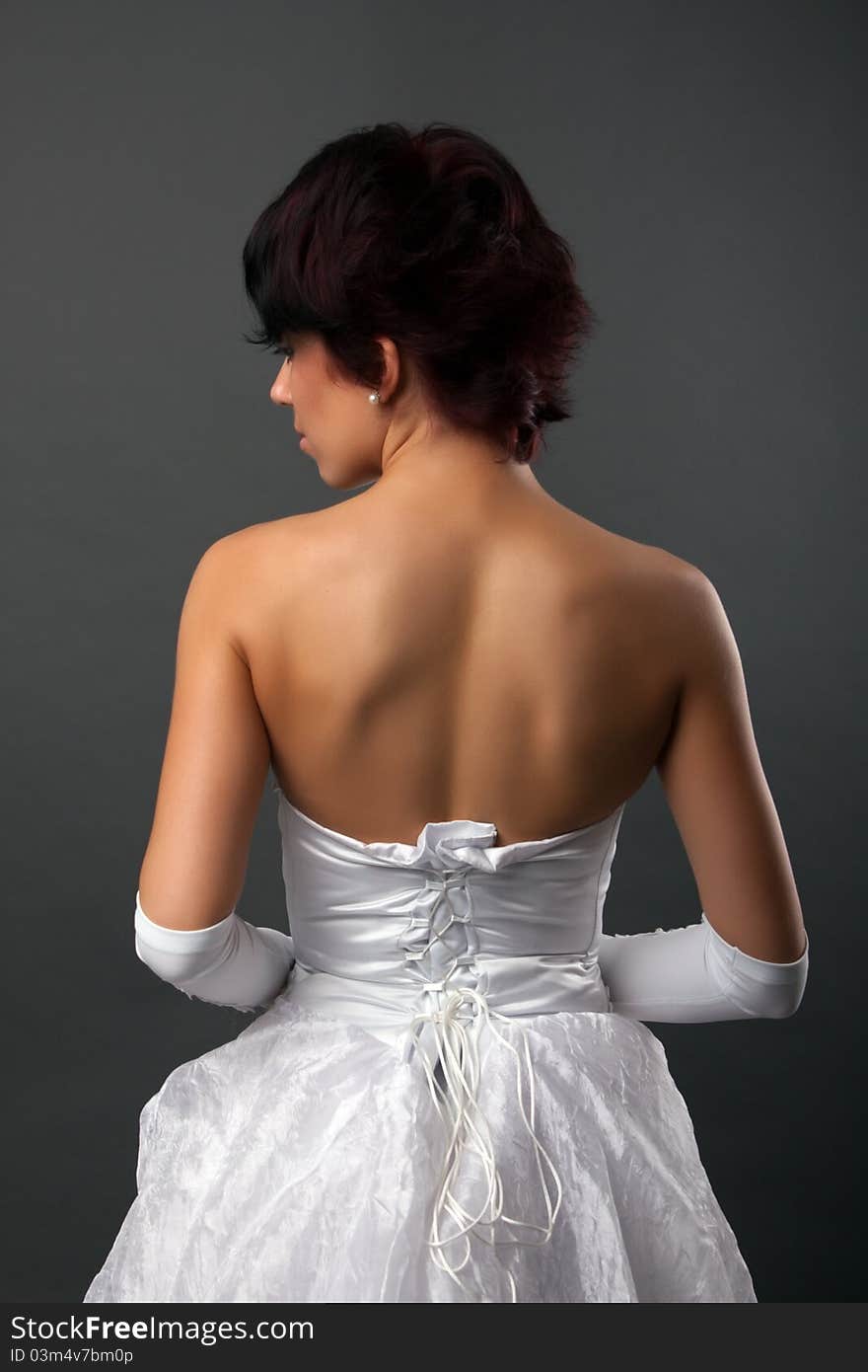 Back view of beautiful brunette bride over gray studio background. Back view of beautiful brunette bride over gray studio background