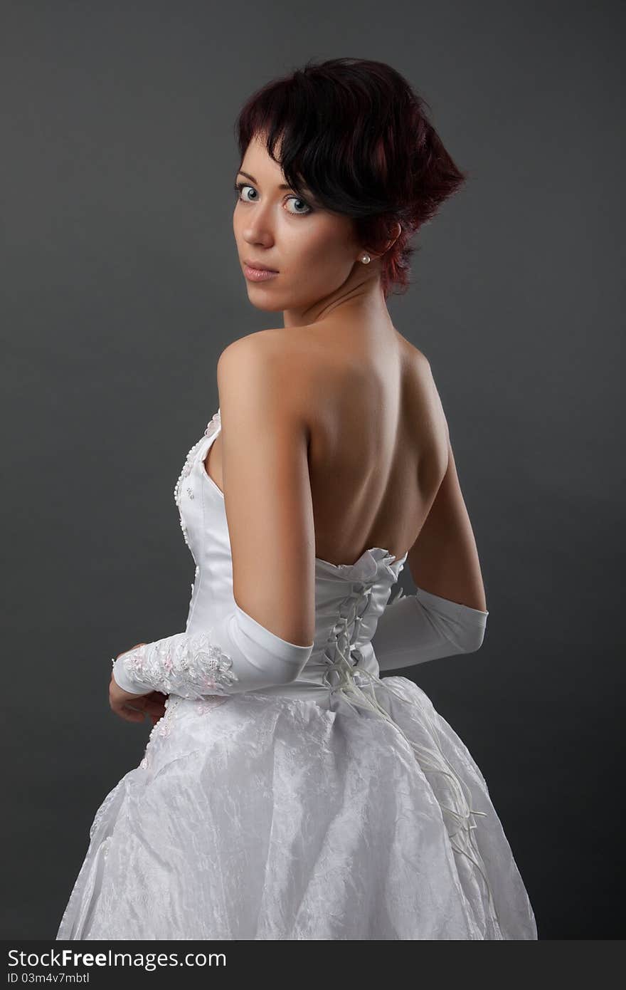 Back view of beautiful brunette bride over gray studio background. Back view of beautiful brunette bride over gray studio background