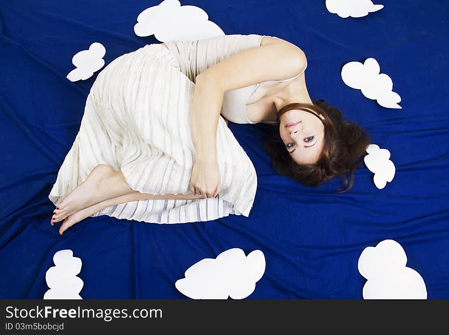 Young beautiful girl lying in the sky with clouds