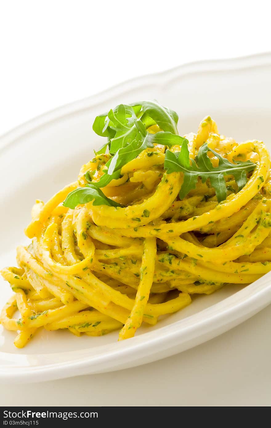 Photo of delicious pasta with saffron and arugula pesto on isolated background. Photo of delicious pasta with saffron and arugula pesto on isolated background