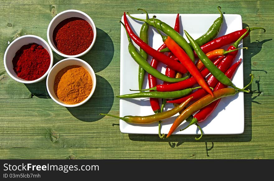 Assorted Chillies Ground and Live on Green Rustic Background