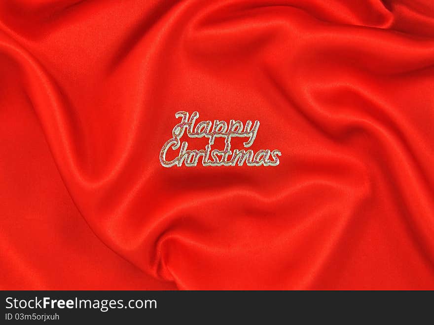 Crumpled red satin cloth with Happy Christmas message. Crumpled red satin cloth with Happy Christmas message