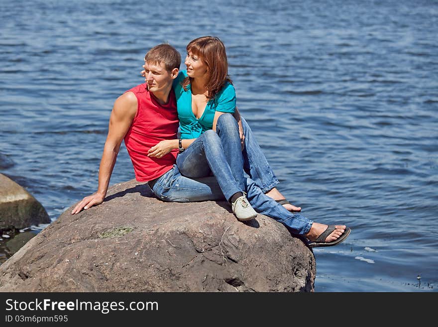 The loving couple sits on a stone on an coast. The loving couple sits on a stone on an coast