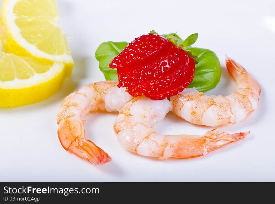 Shrimp with strawberries and lemon on the plate