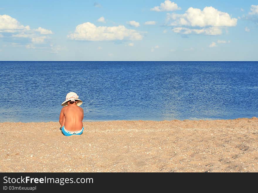 A girl sitting on a summer evening on the beach. A girl sitting on a summer evening on the beach