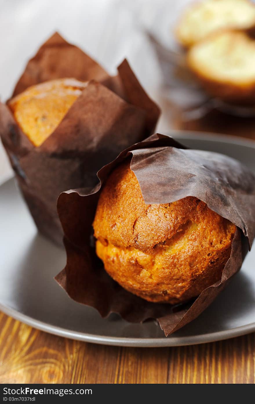 Two muffins on the plate, the dark wooden background.