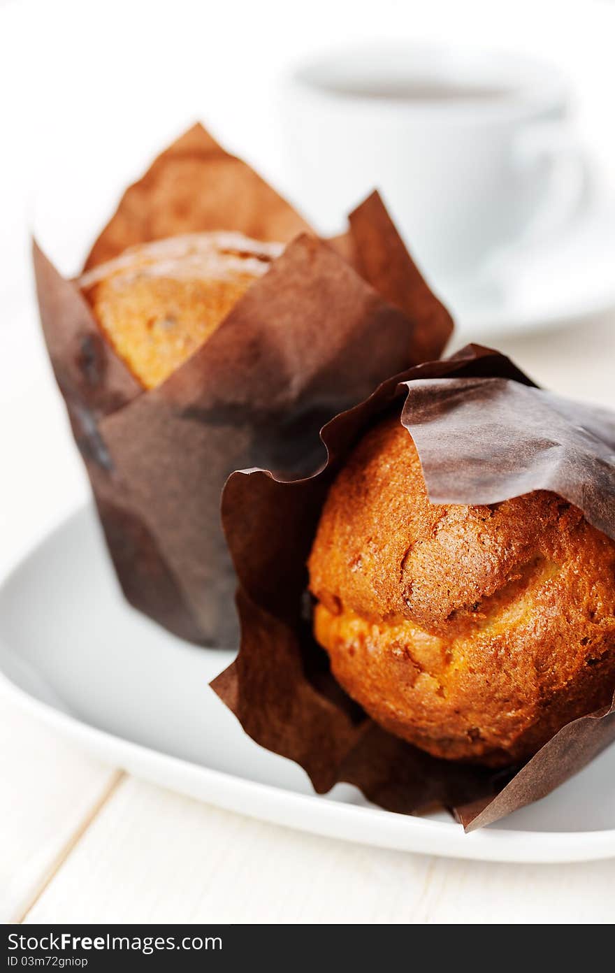 Two muffins on the plate and a cup of tea.