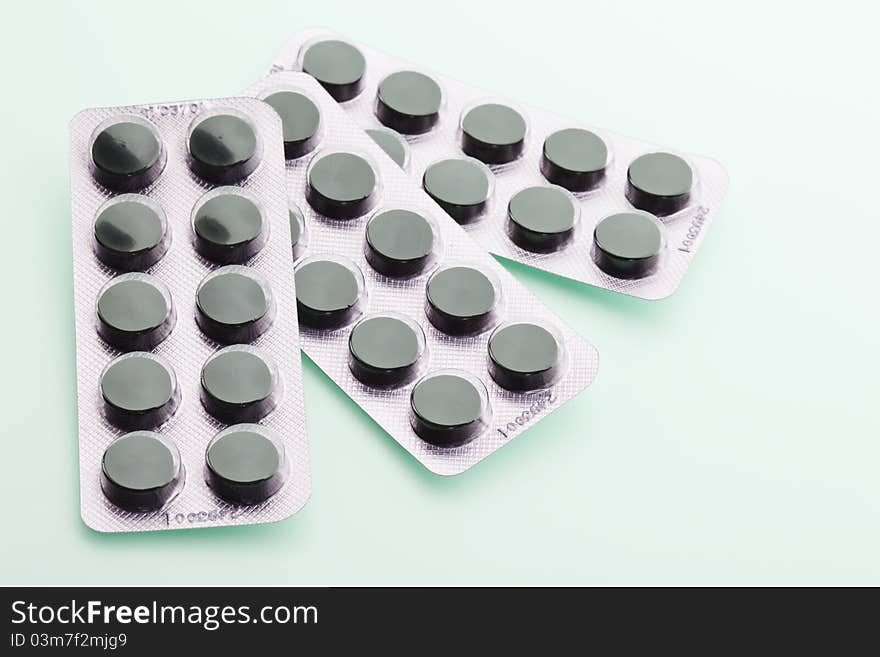 Charcoal tablets in packing material on green background