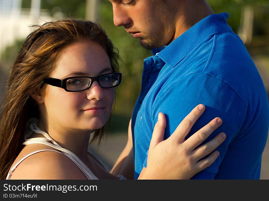 A young woman embraces a young man and is looking at the camera