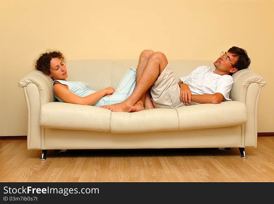 Woman And Man Repose On The White Sofa