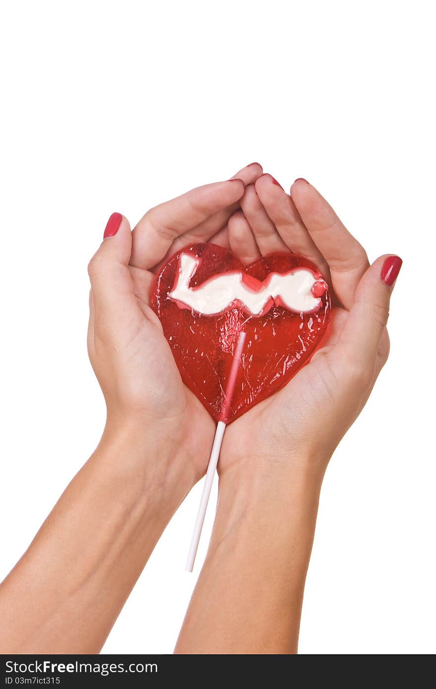 Heart shape lollipop in a hand isolated over white background