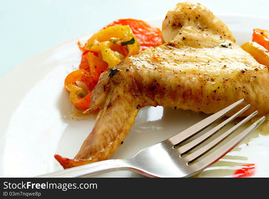 Baked chicken wing on a plate and fork