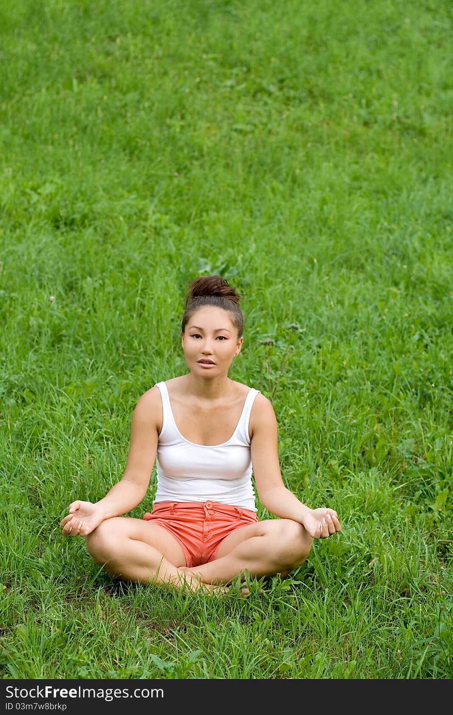 Girl meditating on meadow in park