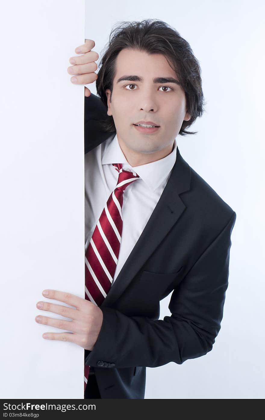 Young man appears from behind a white panel. Young man appears from behind a white panel