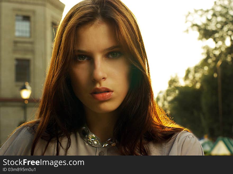 Portrait of a beautiful woman posing at the city street in sunset back light