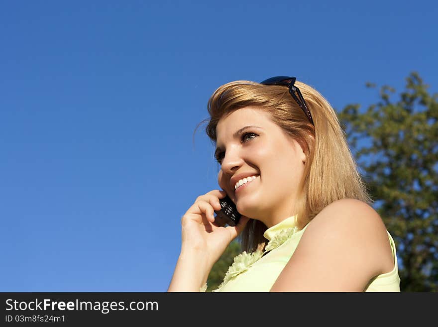 Young smiling woman speaks by mobile phone.