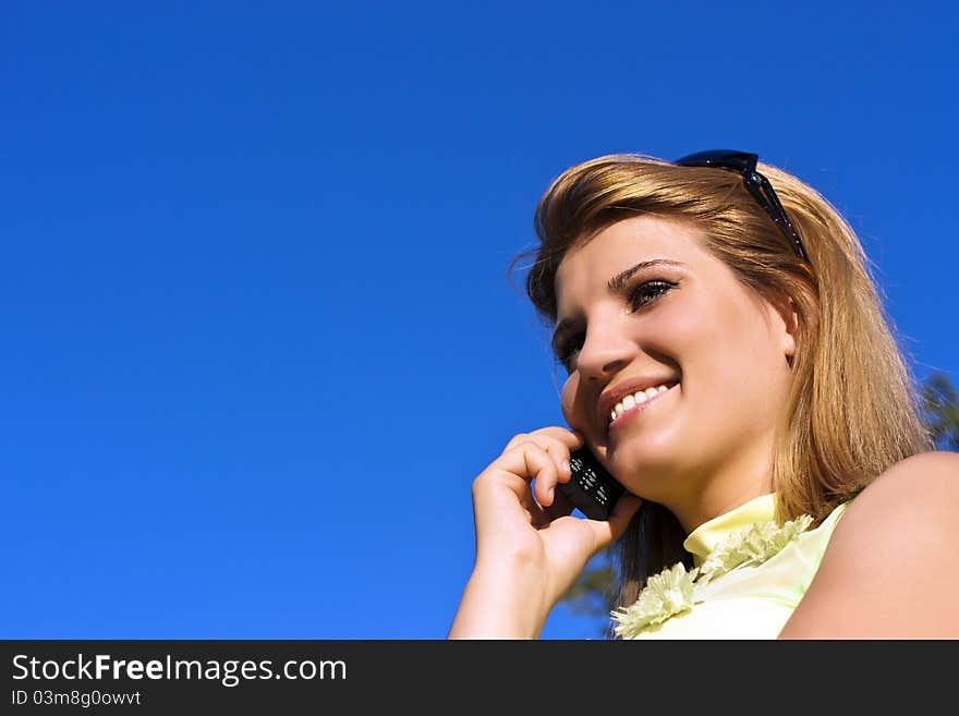 Young smiling woman speaks by mobile phone.