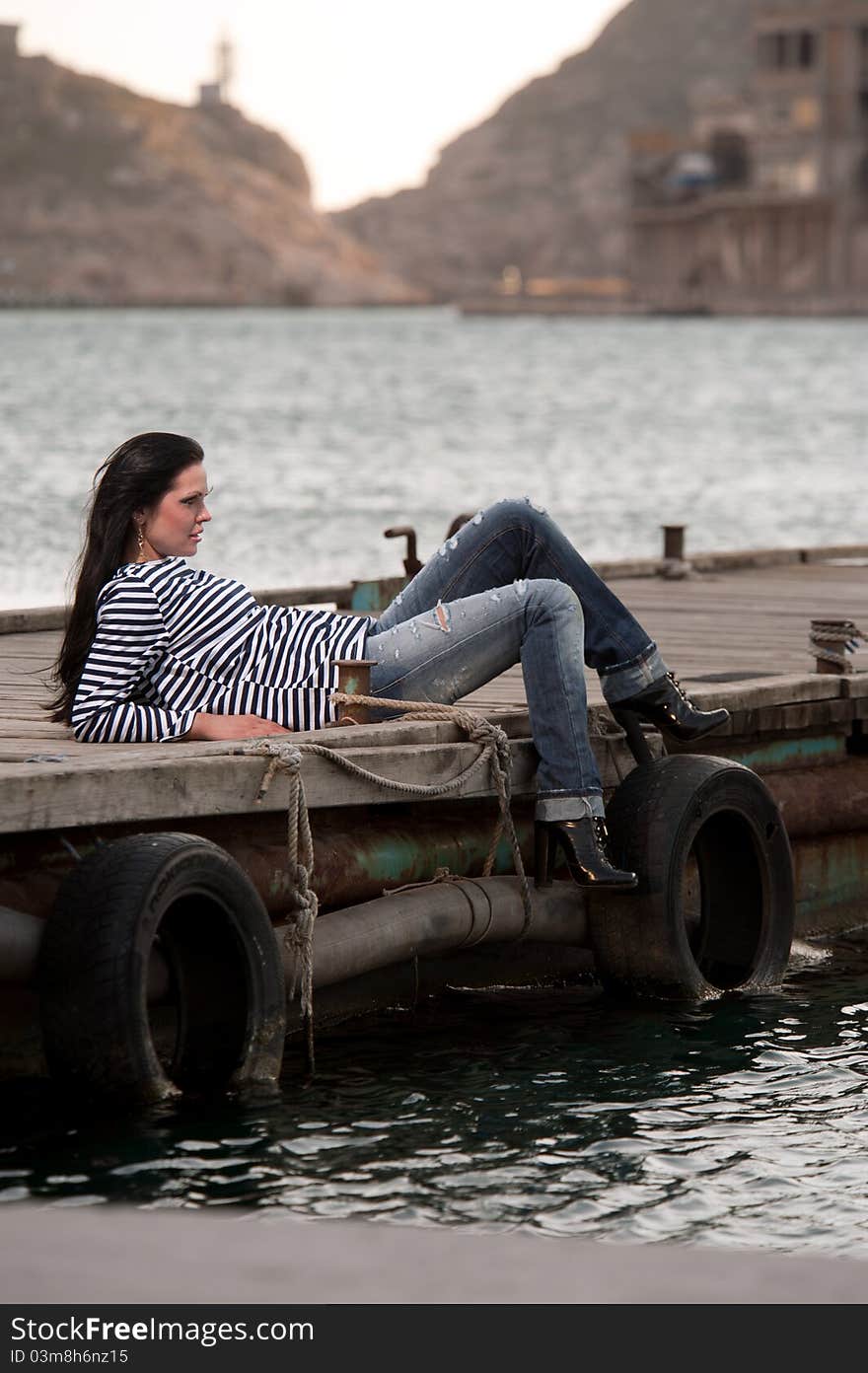 Woman lying on a pier in the background of the sea