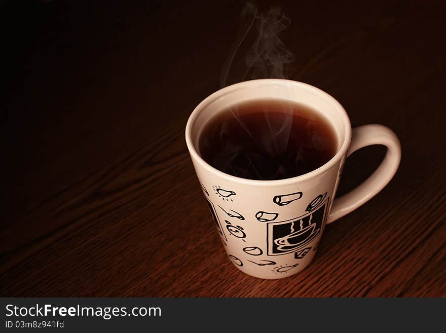 The white cup with steaming hot drink sitting on table. The white cup with steaming hot drink sitting on table