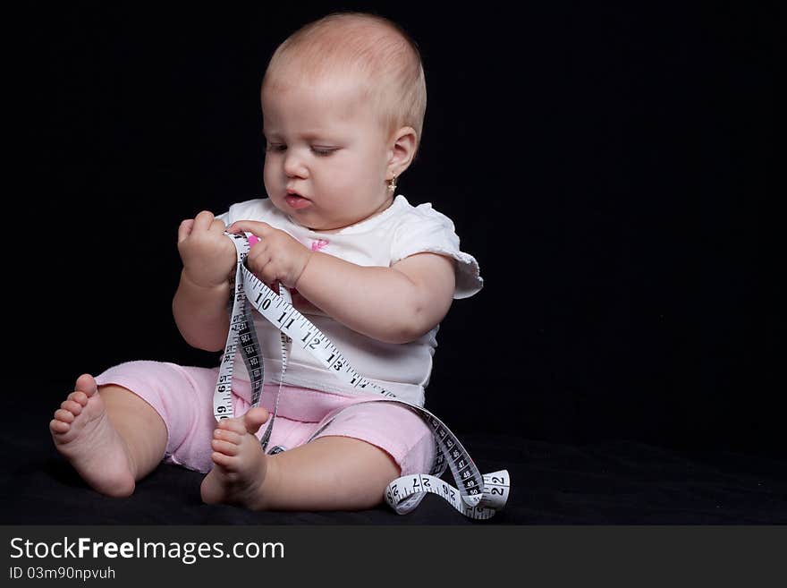 Little baby girl measuring with a meter on black background. Little baby girl measuring with a meter on black background