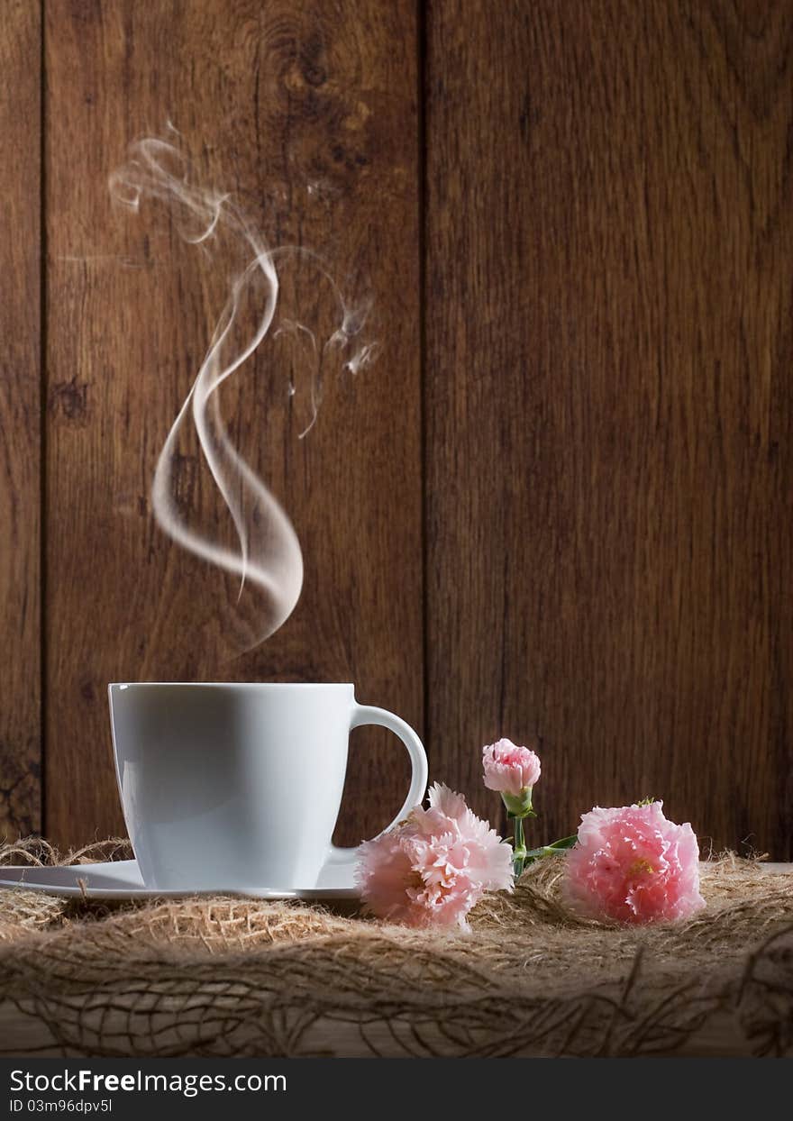 Cup of coffee with flowers on wooden background