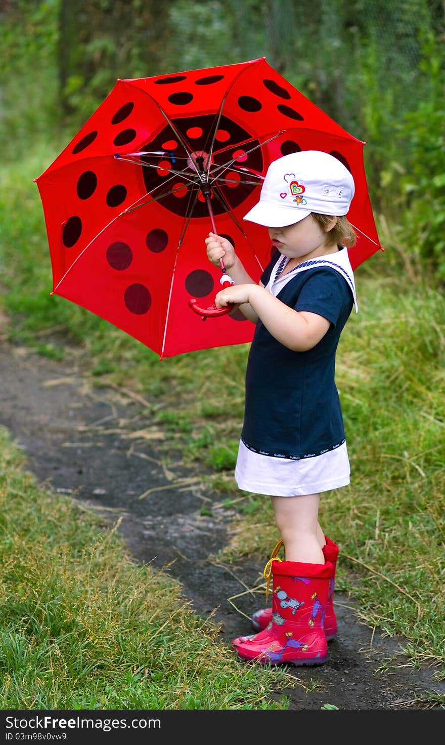 The little girl with an umbrella and in rubber boots