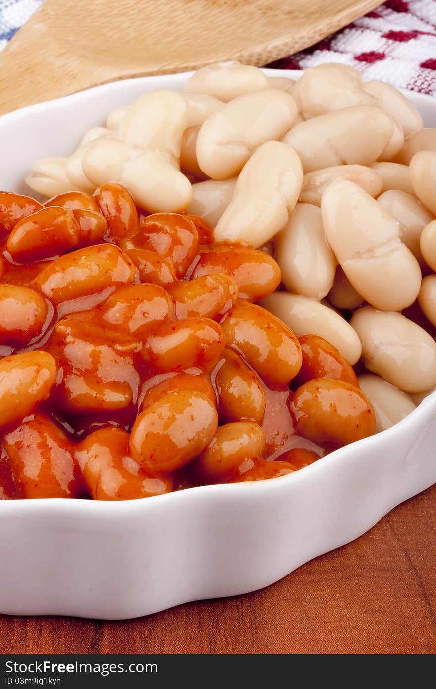 White canned beans in a white ceramic dish with red sauce. White canned beans in a white ceramic dish with red sauce.