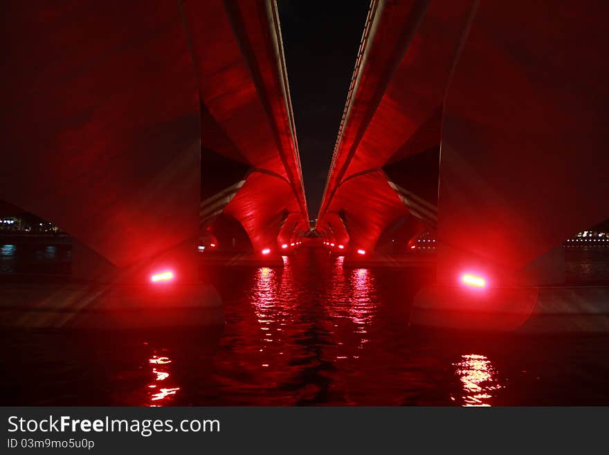 Bright red light give some life into this old bridge at night.