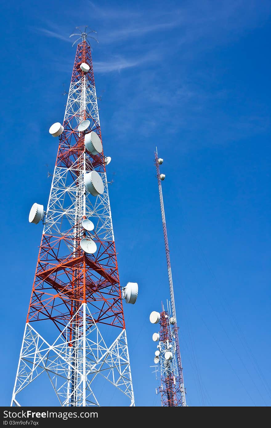 Broadcaster or transmitter tower with telecommunication satellites on blue sky