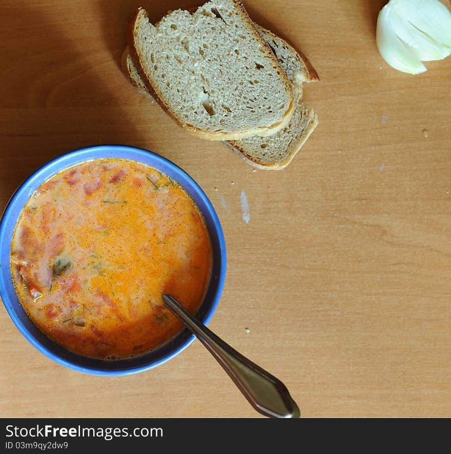 An image of a bowl of soup, onion and bread on the table. An image of a bowl of soup, onion and bread on the table