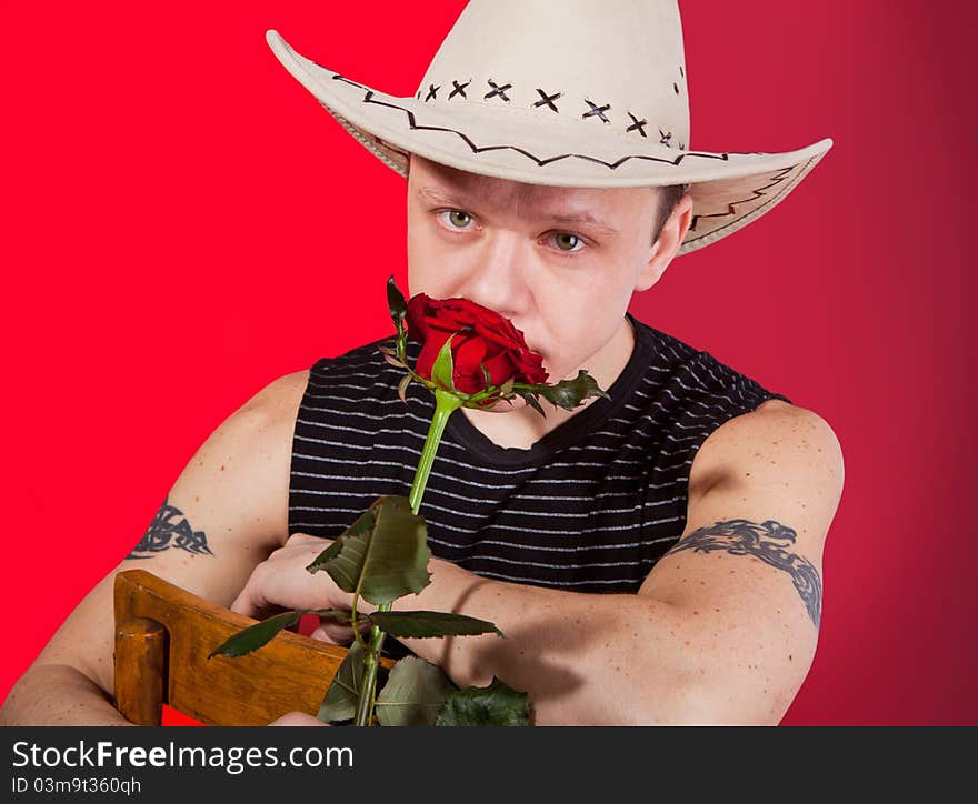 A muscular man in a cowboy hat with red rose