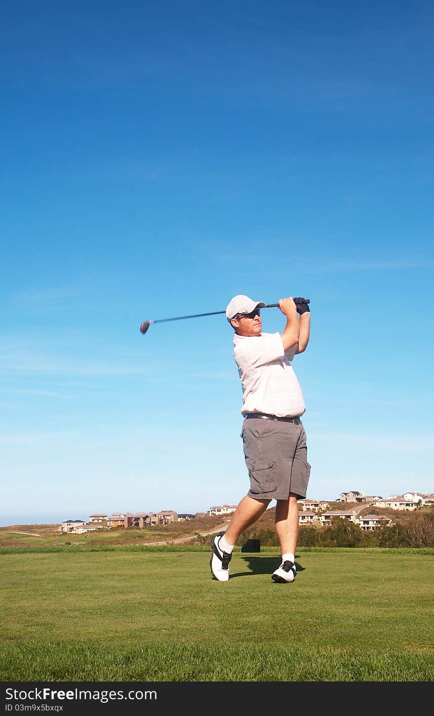 Young male golfer playing off the tee box on a summer day