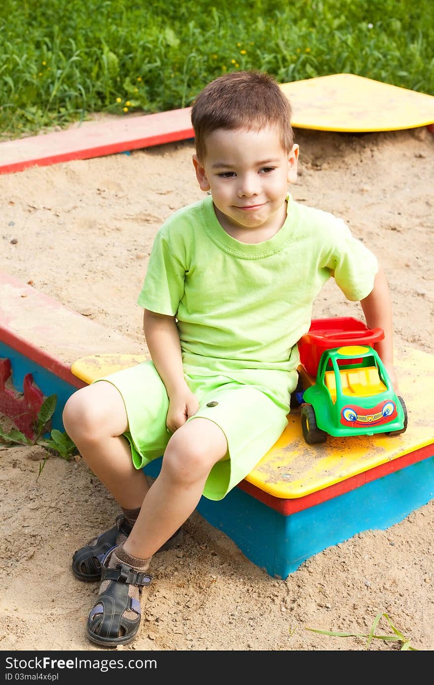 A little boy smiling and playing in the toy car