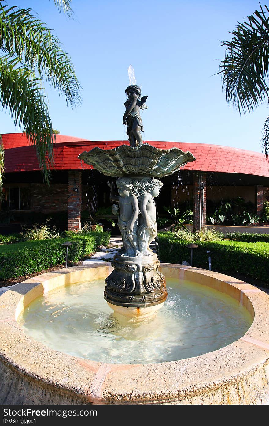 Classic water fountain in front of building. Tropical location on a sunny day.