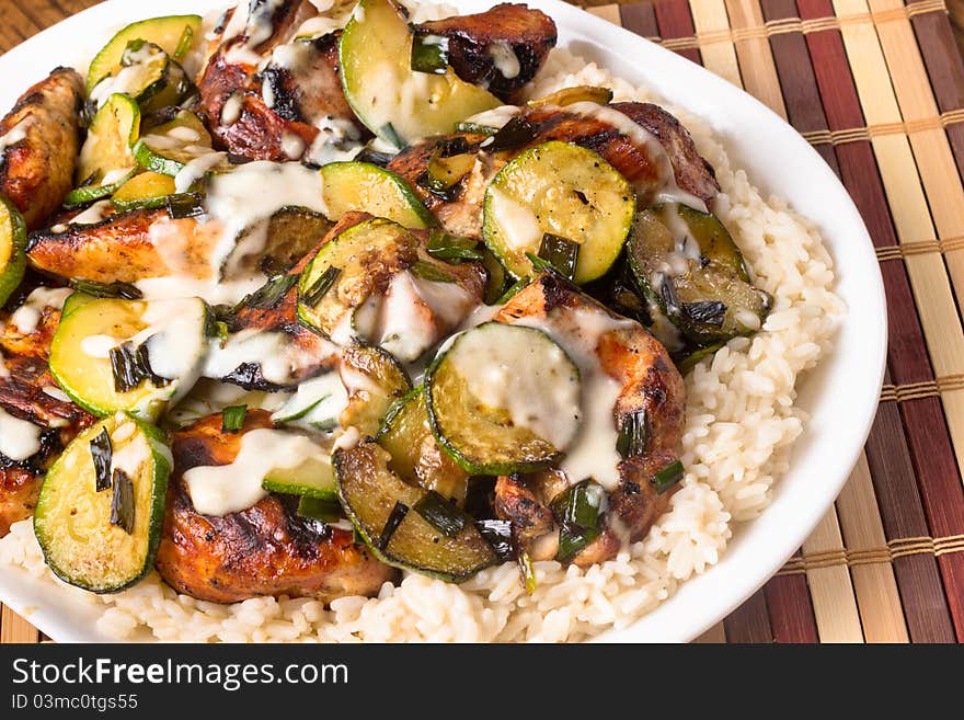 A plate of delicious chicken with zucchini served over white rice. A plate of delicious chicken with zucchini served over white rice