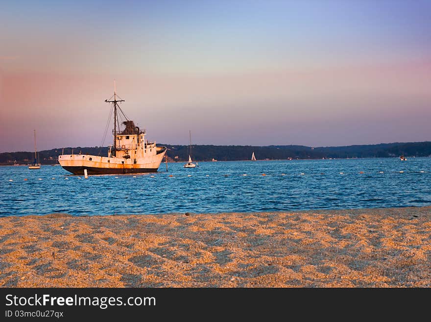 Fishing boat at the end of the day with golden sun falling on the beach