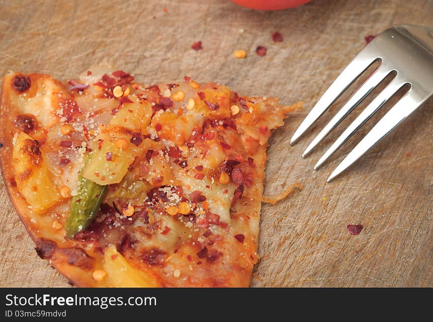 Closeup shot of single pizza slice with fork on wooden background. Closeup shot of single pizza slice with fork on wooden background.
