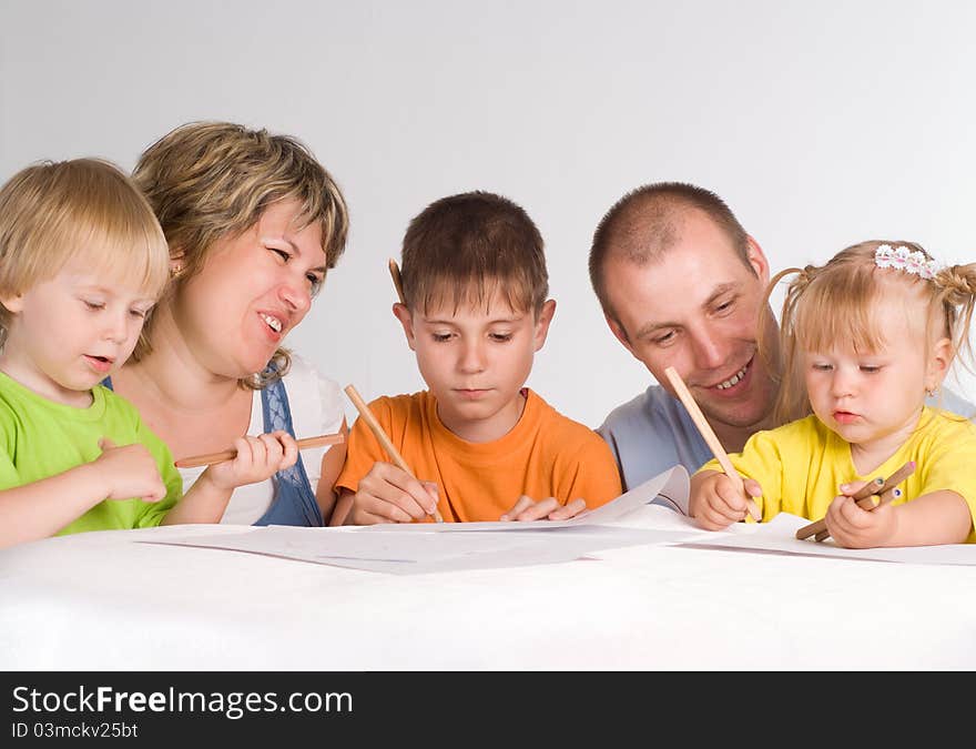 Happy family drawing at the table on a white