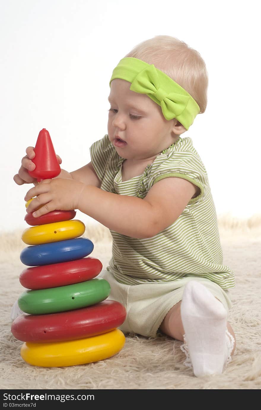 Little girl playing on a carpet with toy