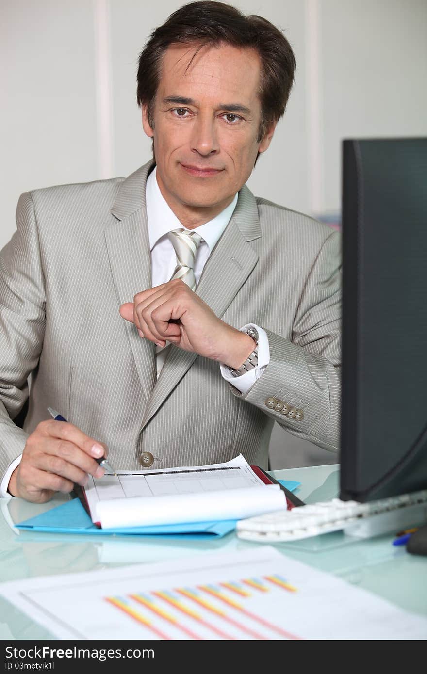 Businessman filling out a form at his desk. Businessman filling out a form at his desk